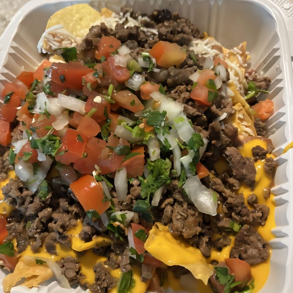 Close-up of Super Burrito & Taqueria's carne asada nachos with pico de gallo, cheese, and sour cream.