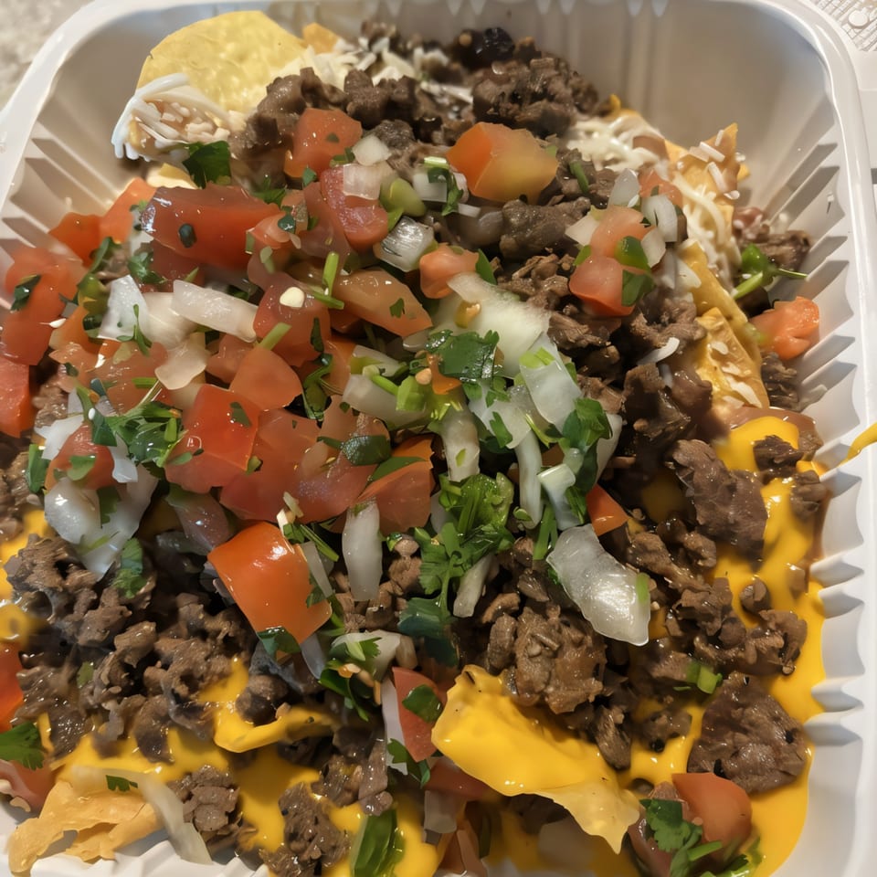 Close-up of Super Burrito & Taqueria's carne asada nachos with pico de gallo, cheese, and sour cream.